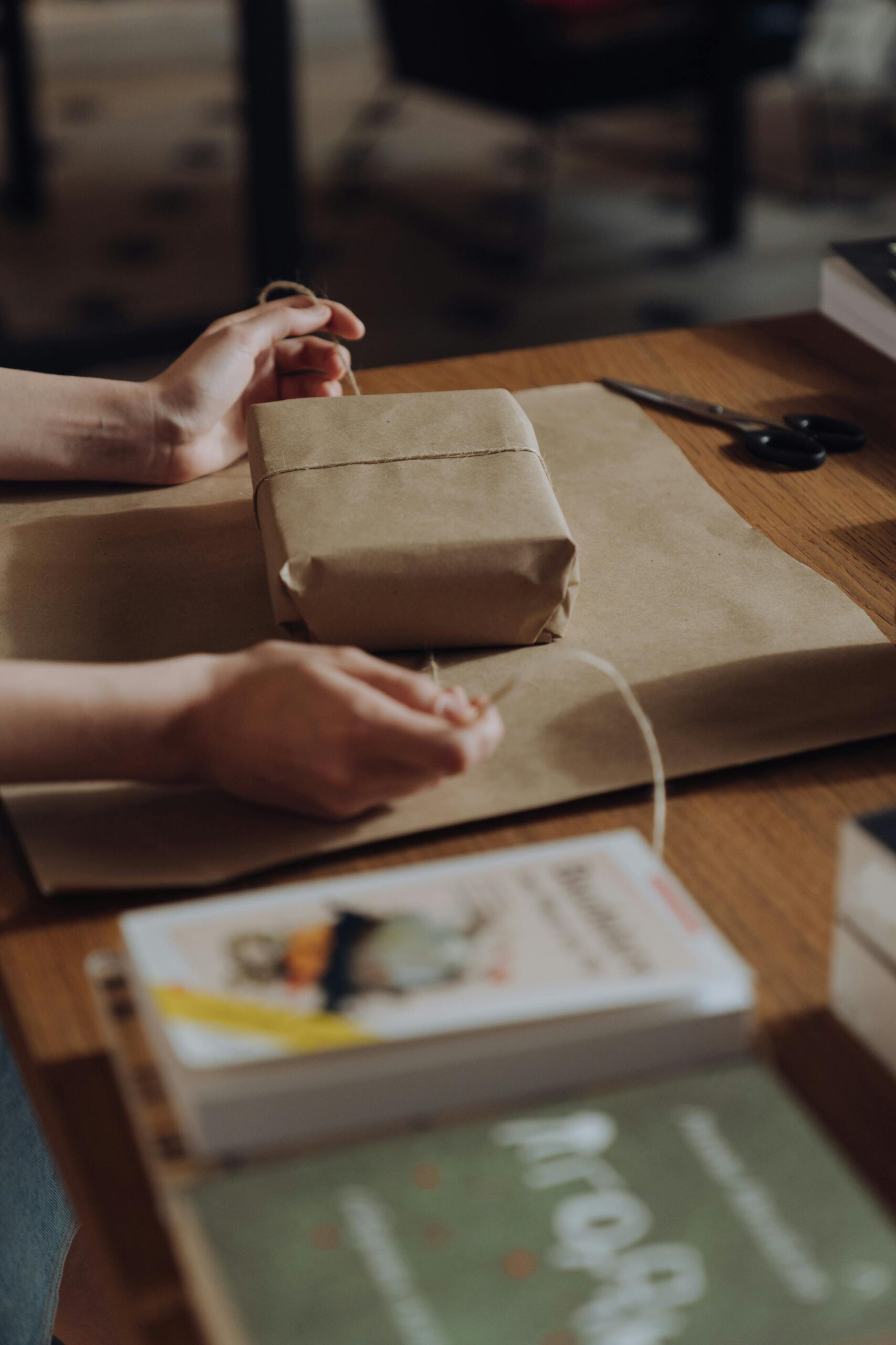 Hands skillfully wrapping a book with brown craft paper in a bookstore setting.