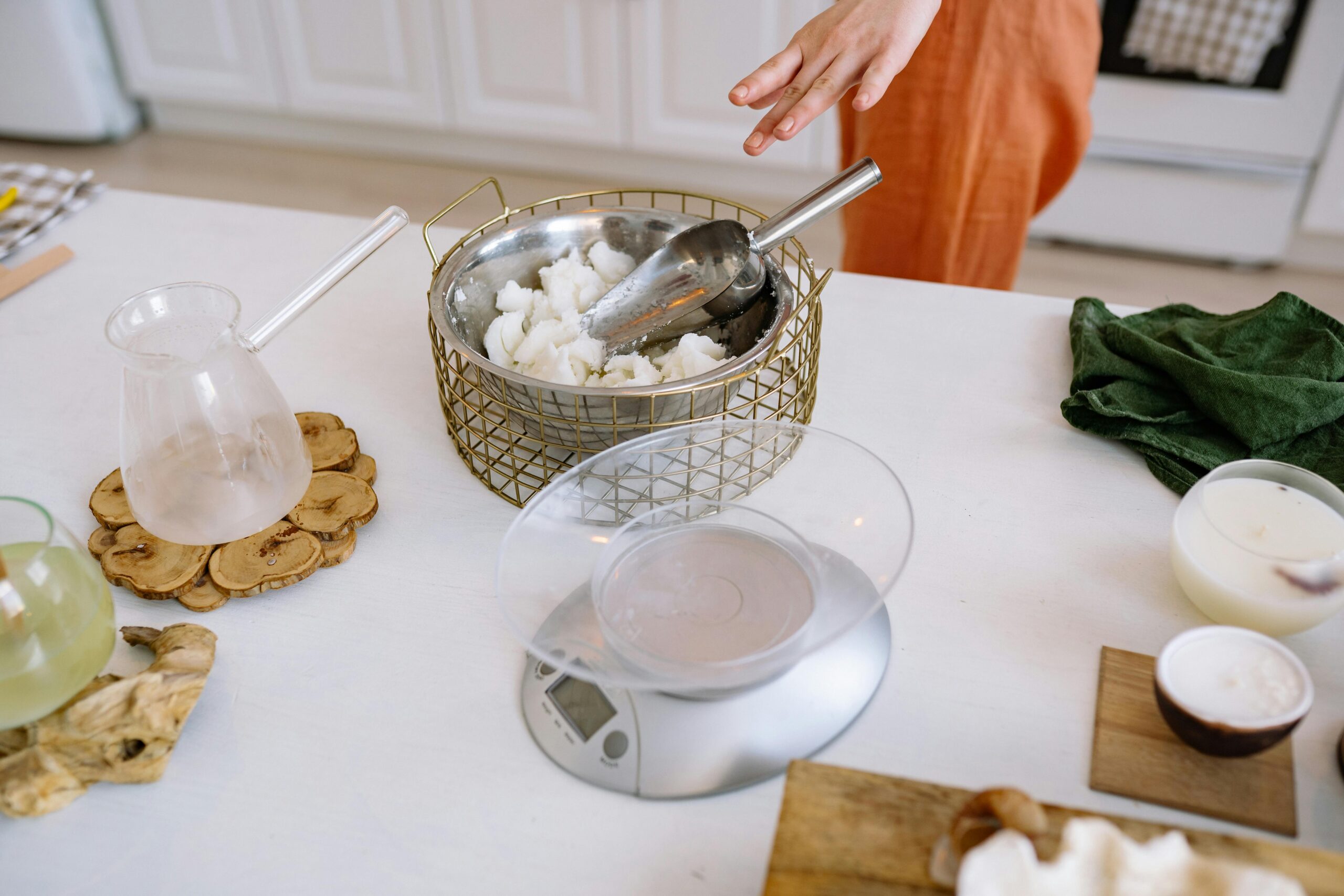 A person crafting handmade candles in a cozy kitchen with natural materials.